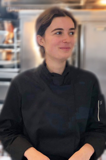 Bertille, portant une veste noire, dans un environnement de cuisine professionnelle.