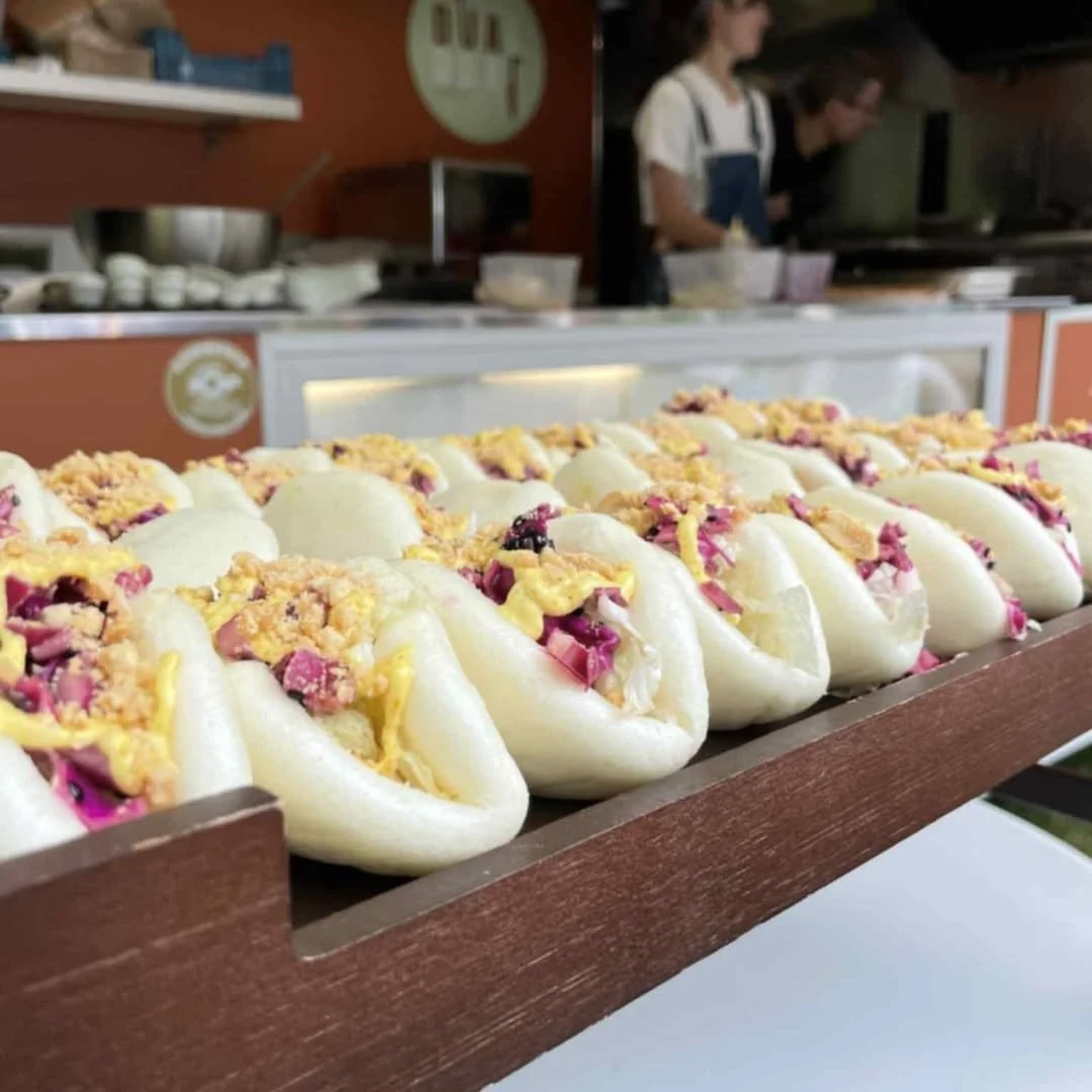 Pain buns garnis de garniture savoureuse sur un plateau en bois, servi par dual food traiteur.