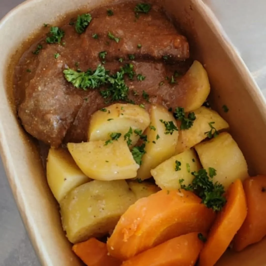 Plat de viande et légumes, avec pommes de terre, carottes, et garniture de persil.