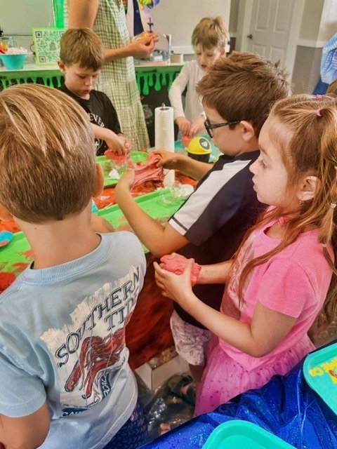 Children gathered around a table, having fun making their own slime at a 67 Slime Co. Mobile Lab Birthday Party.