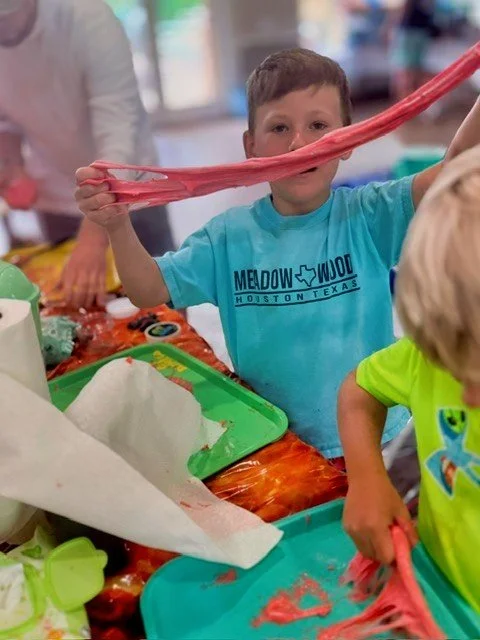 Children playing and having fun making their custom creation pink stretchy slime at the 67 Slime Co. Mobile Lab Party.