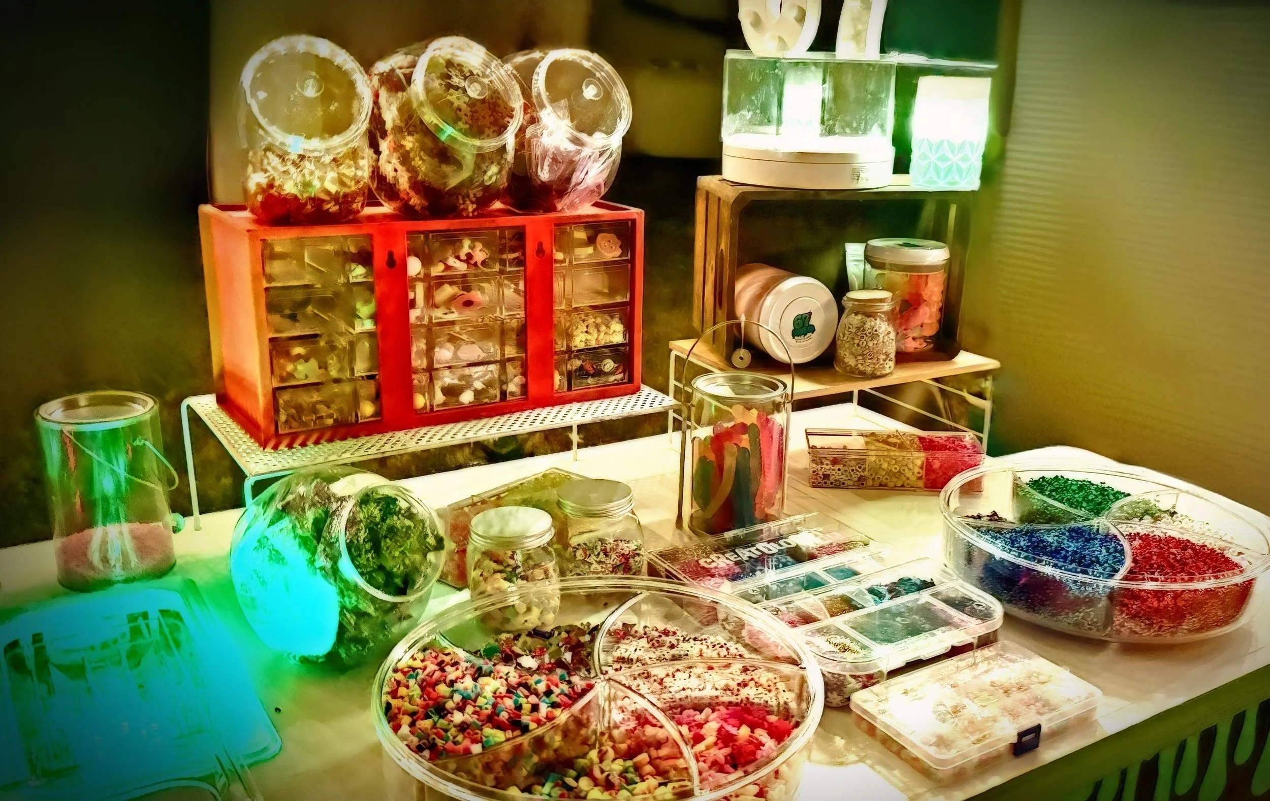 Display of various jars and containers filled with colorful craft supplies like beads, sequins, and decorative items on a table at a craft booth.