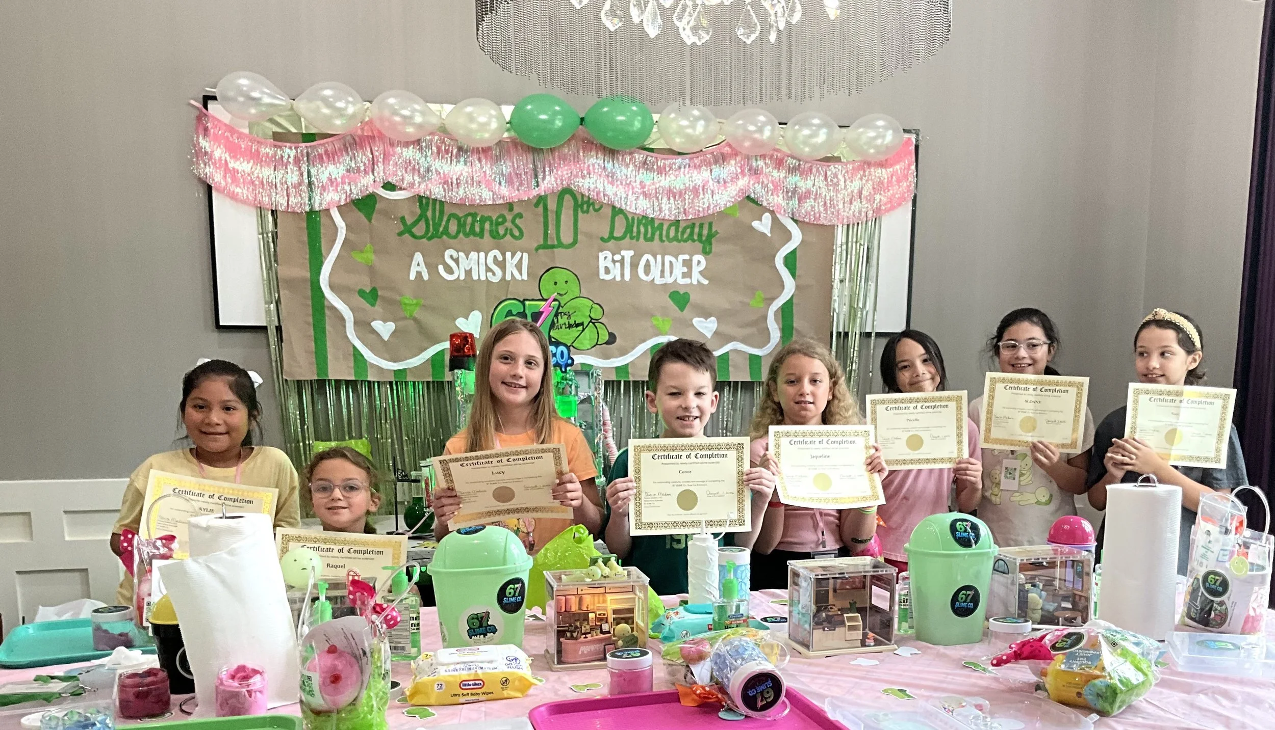 Children at a birthday party holding their 67 SLIME Co. Slime Scientist certificatesthey had just been awarded at a10th birthday  party.