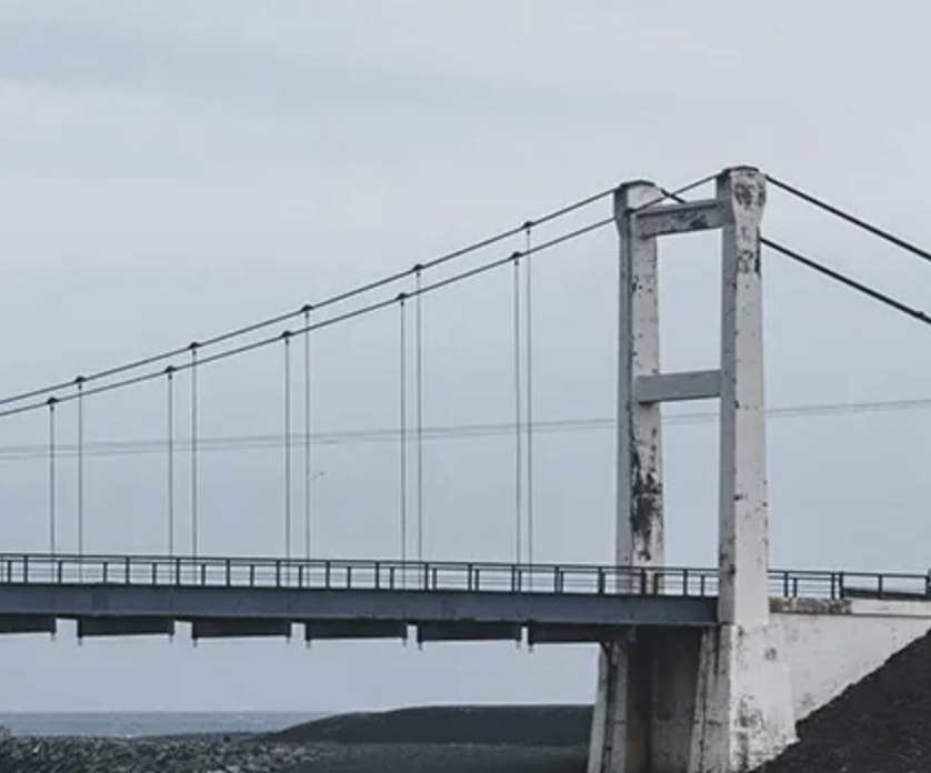 Suspension bridge with weathered towers and cables, symbolising InSAR-based monitoring of bridge foundations and approach embankment stability.