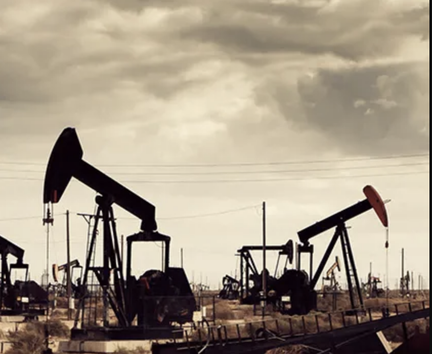 Oil pumps in a desert landscape under cloudy skies, showing typical fields where InSAR monitoring is used to track subsidence and induced seismic risk.