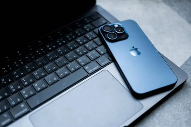Clavier d'ordinateur portable avec un iPhone 13 Pro posé dessus.