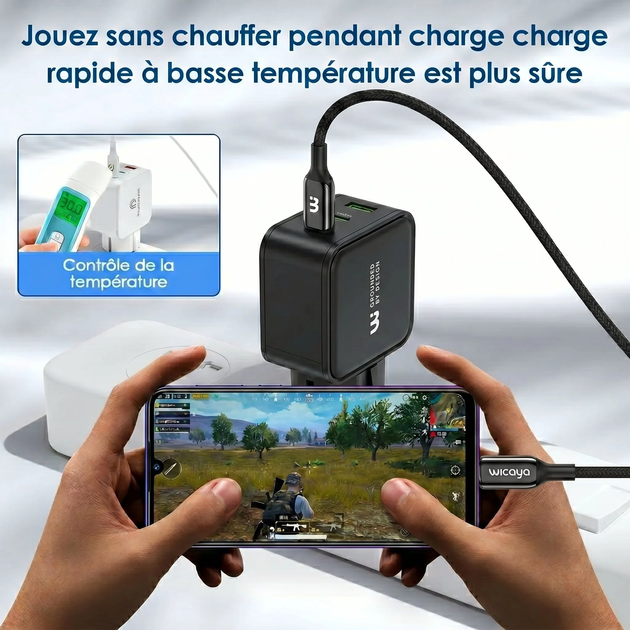Personne tenant un téléphone portable en charge sur un wicaya affichant un jeu vidéo.