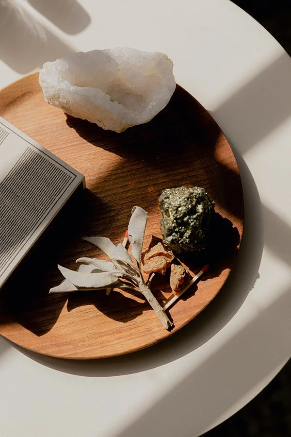 A round wooden plate holding a crystal and a rock bathed in natural sunlight.