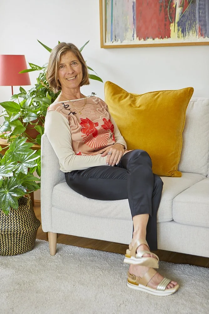 Nora Rose Zinerman relaxing on a sofa with an open smile.