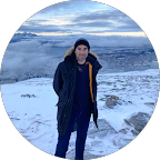 Personne debout dans un paysage hivernal avec neige, vêtue d'un manteau et d'un sac à dos