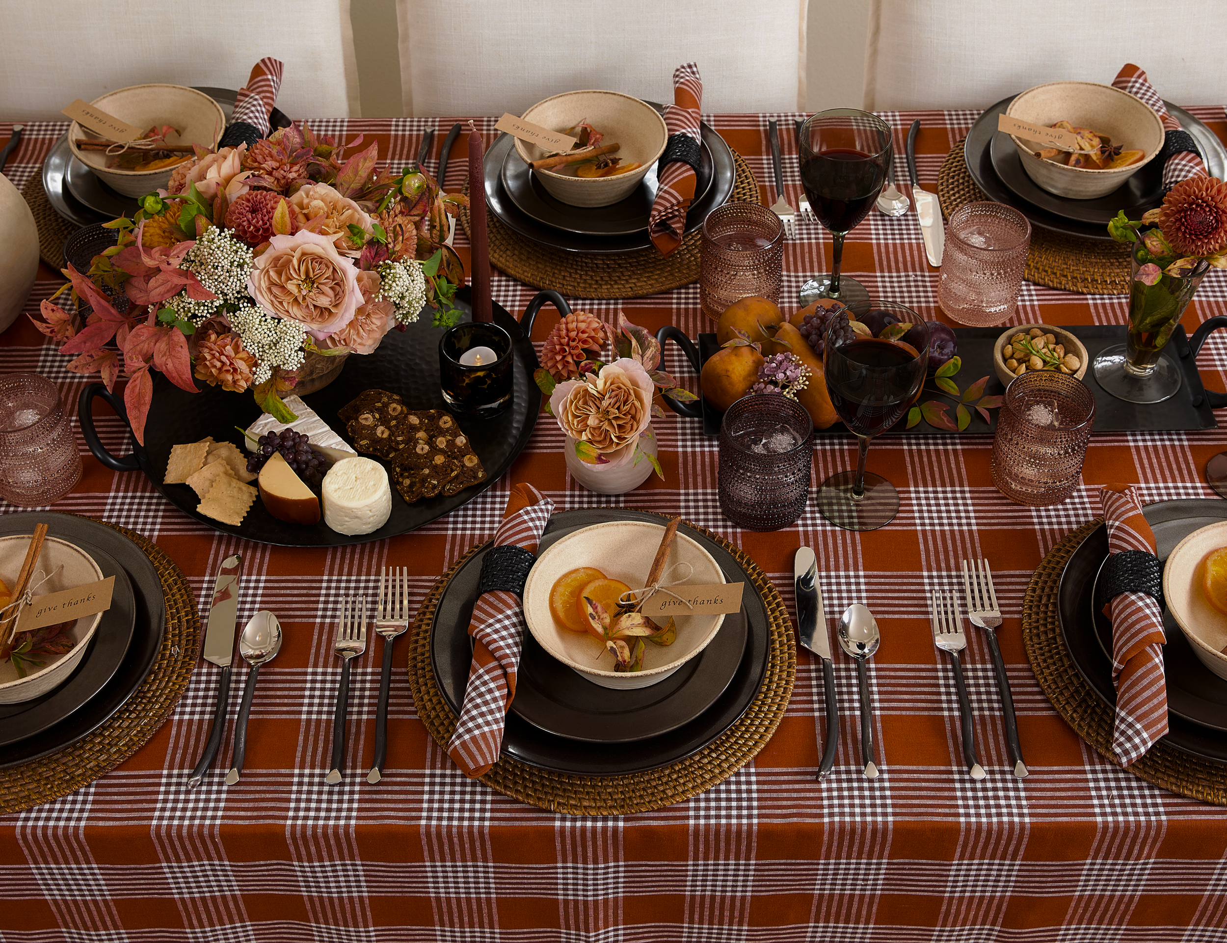 Decorated dining table with floral centerpieces, appetizers, wine glasses, and place settings for a meal with fall-themed colors.