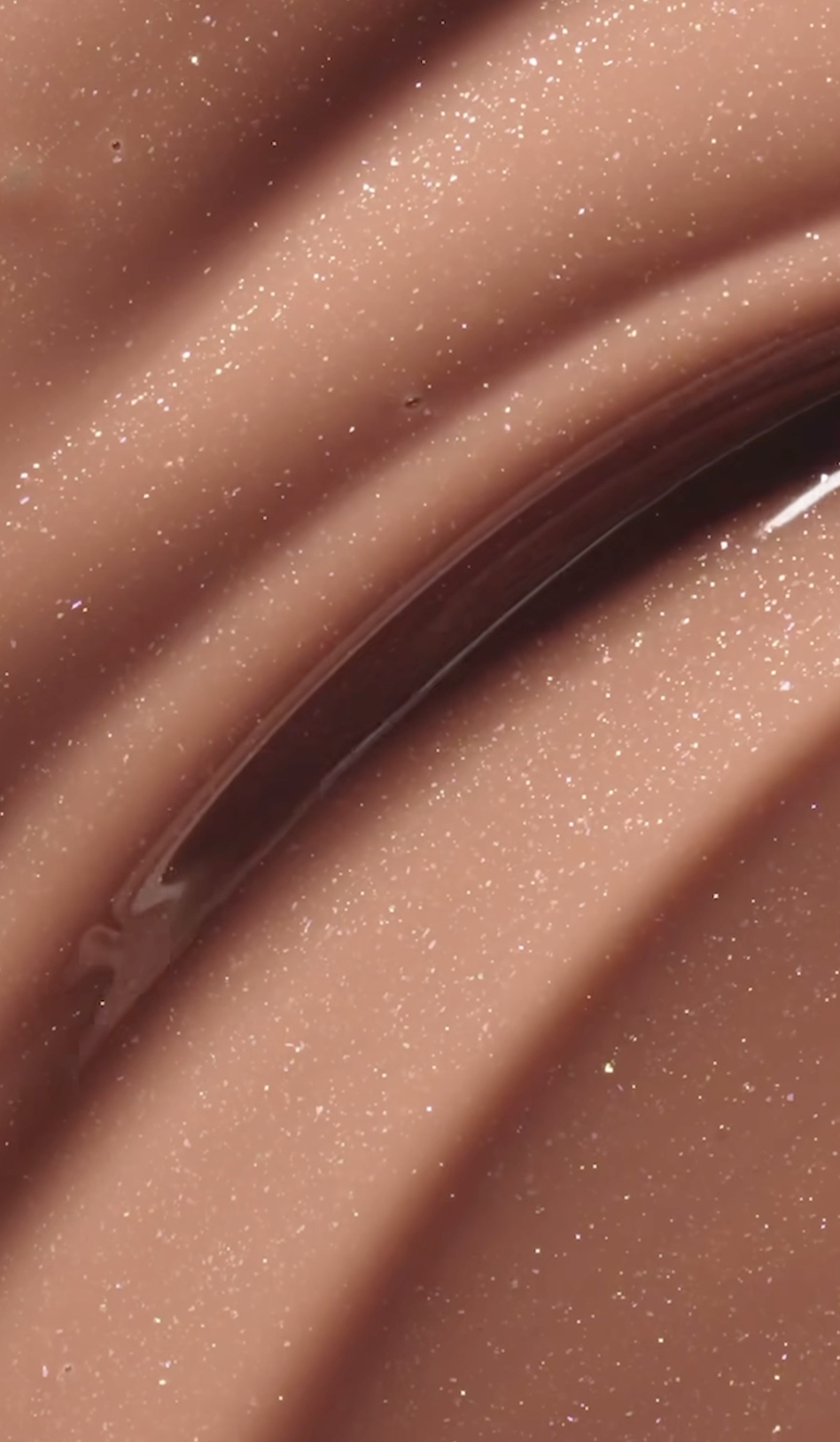 Close-up of a textured, glittery, pinkish surface with a dark shiny curved object or line.