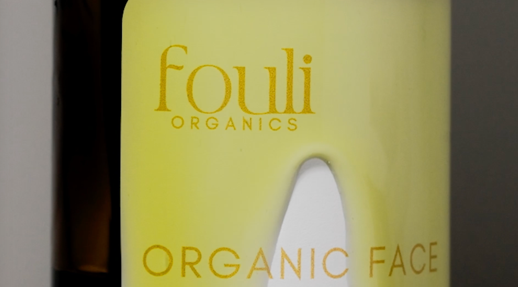 Close-up of a yellow bottle label with the text "Fouli Organics" and "Organic Face".