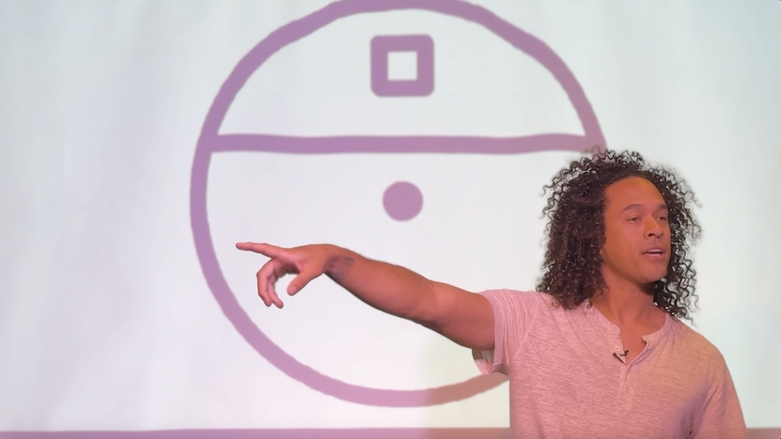 A person with curly hair pointing to a diagram of a tic-tac-toe game on a whiteboard