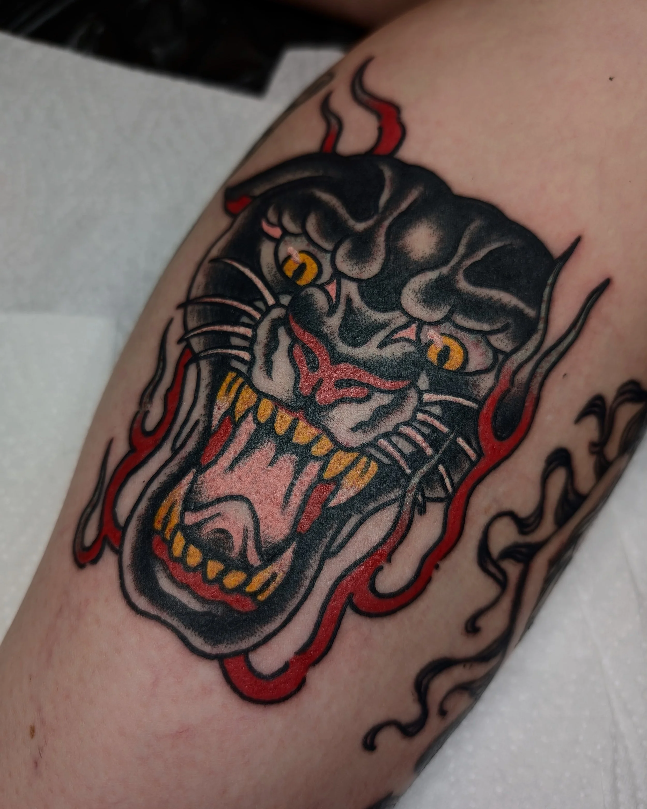 Tattoo eines wütenden Tigers mit offenen Mund,  schwarze, rote und gelbe Farben auf der Haut.