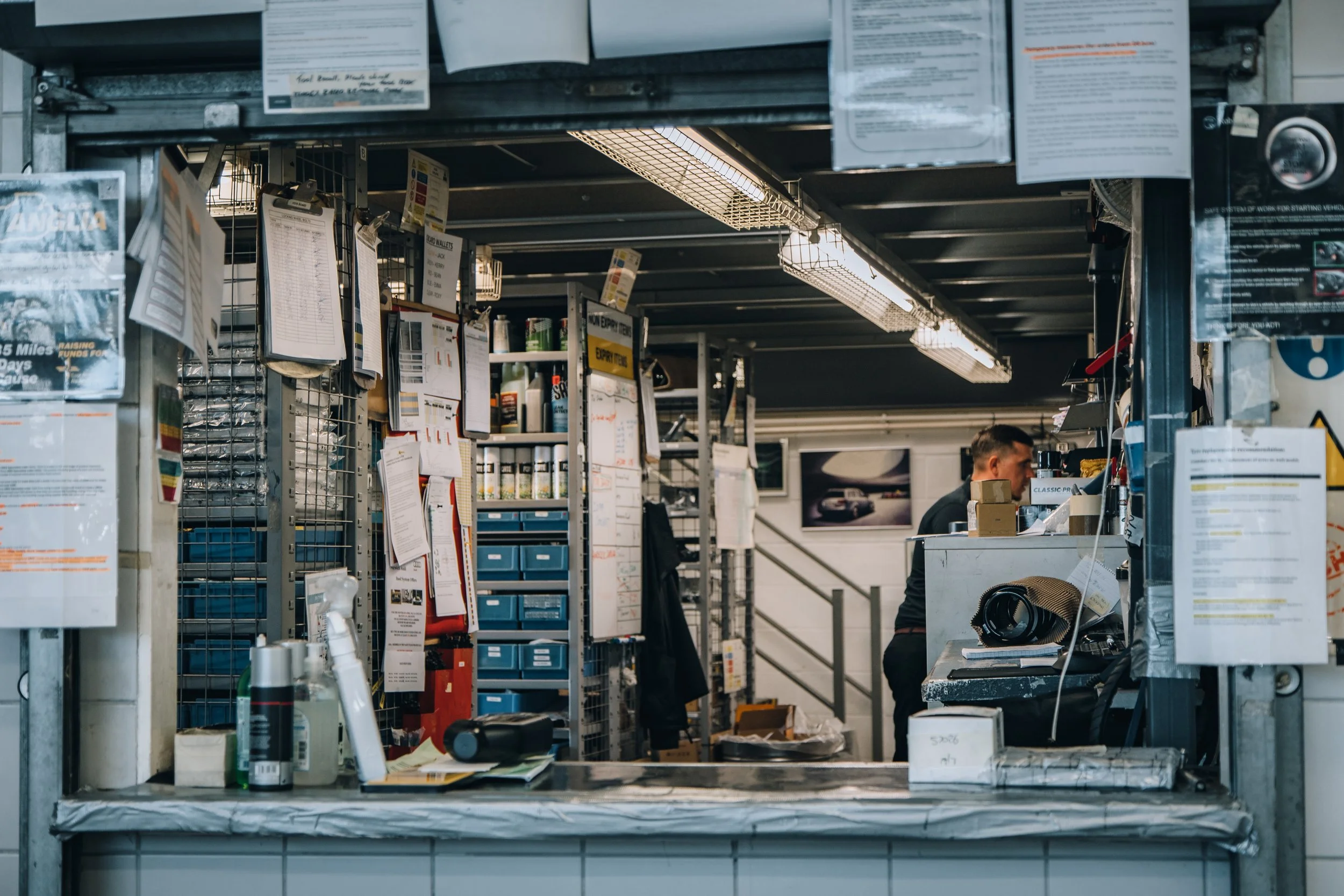 View of a service counter at a tire shop with various tools and notices, with an employee working behind the counter.