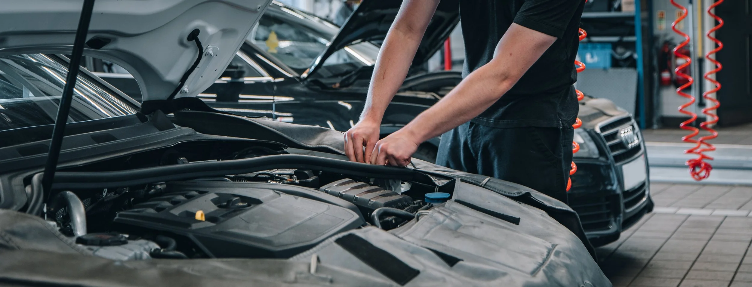 A mechanic working on the engine of a car in an auto repair shop.