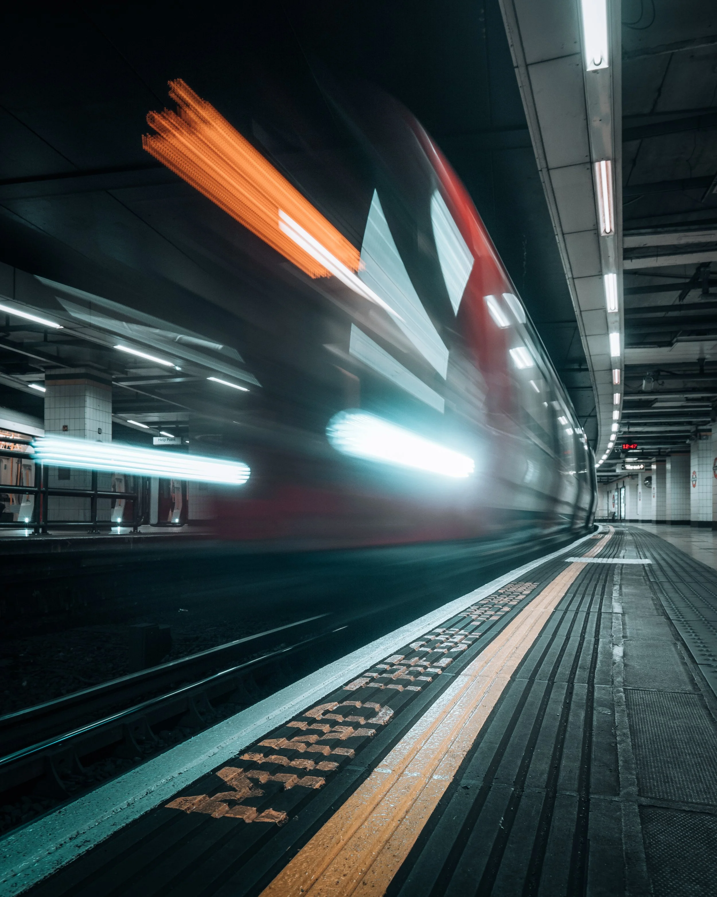 A subway train arriving at an underground station with motion blur, illuminated lights, and tile walls.