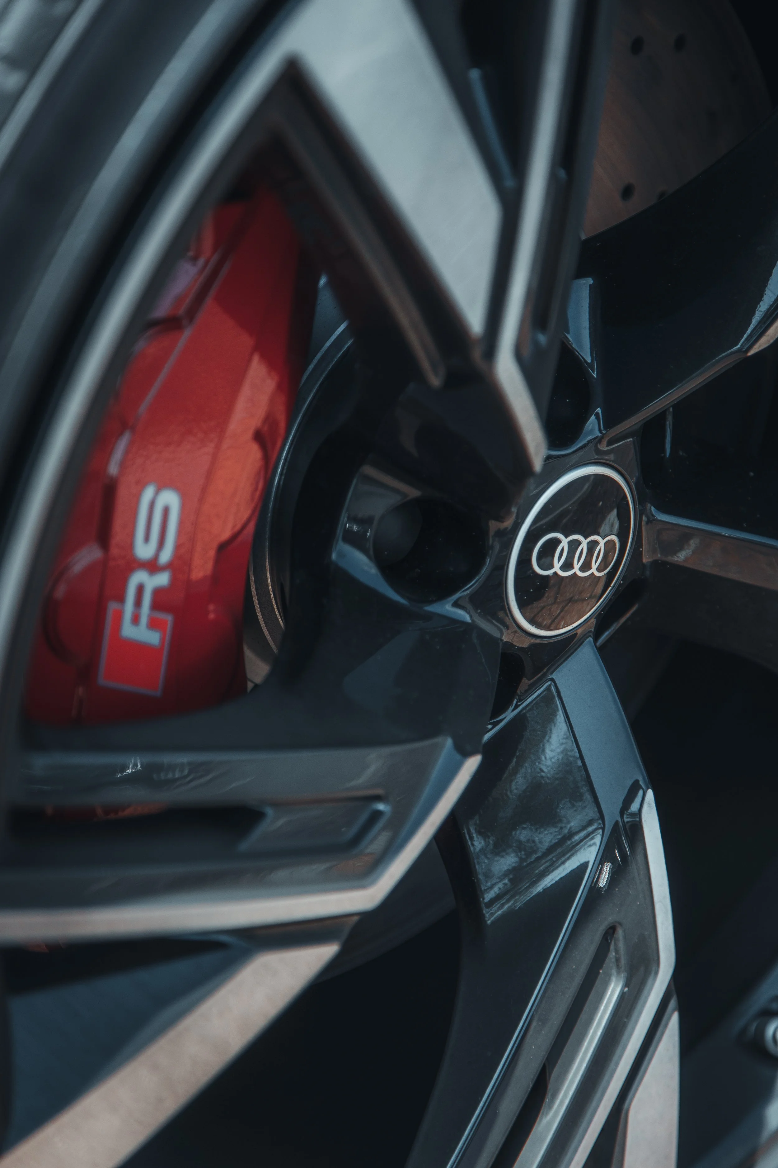 Close-up of an Audi wheel with a red brake caliper that has 'RS' written on it.