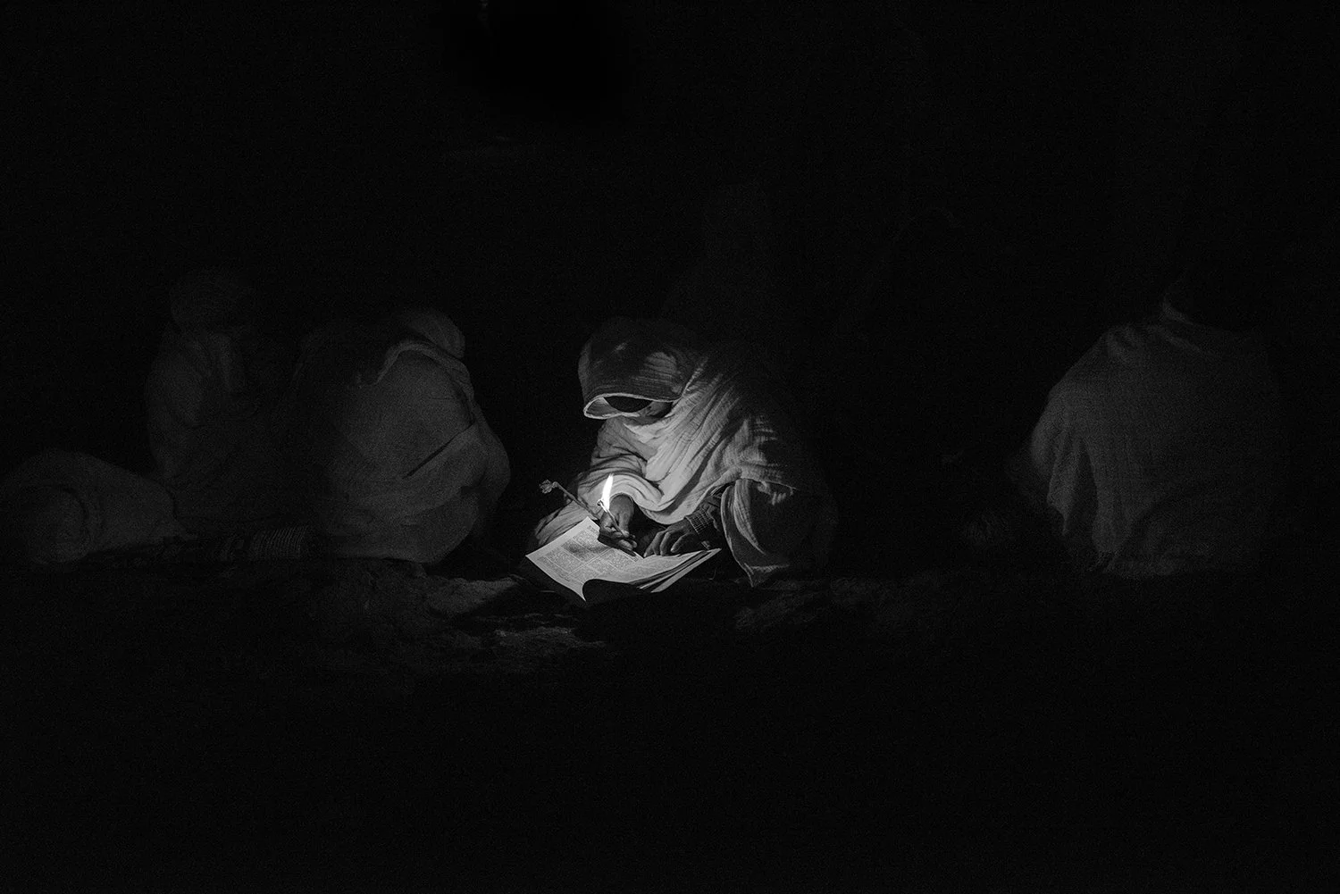 Persona leyendo un libro con una linterna en un entorno oscuro