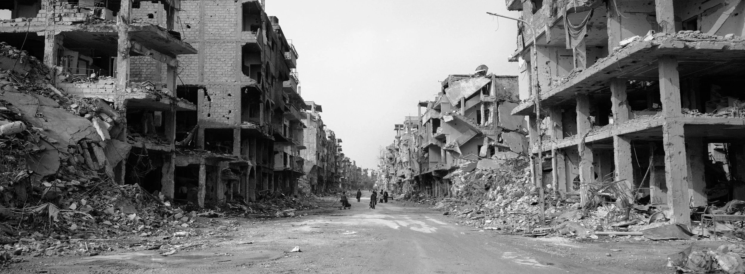 Calles urbanas con edificios dañados y escombros, en un entorno destruido y desolado.