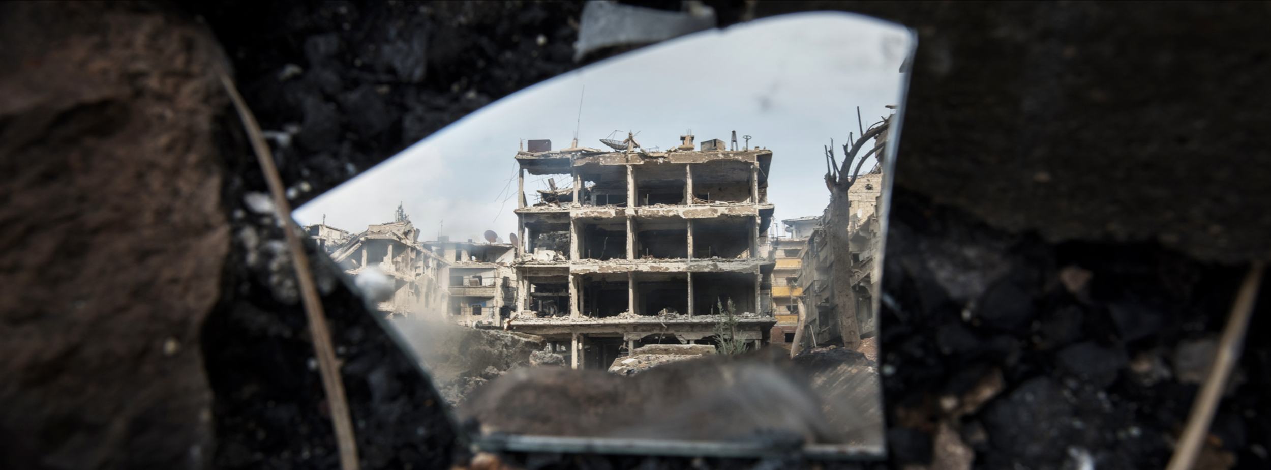 Edificio destruido visto a través de una apertura en el escombro, con daños visibles y daños en la estructura.