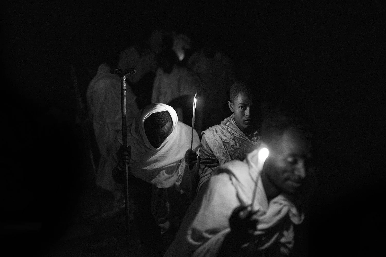 Personas caminando en la oscuridad con velas en mano