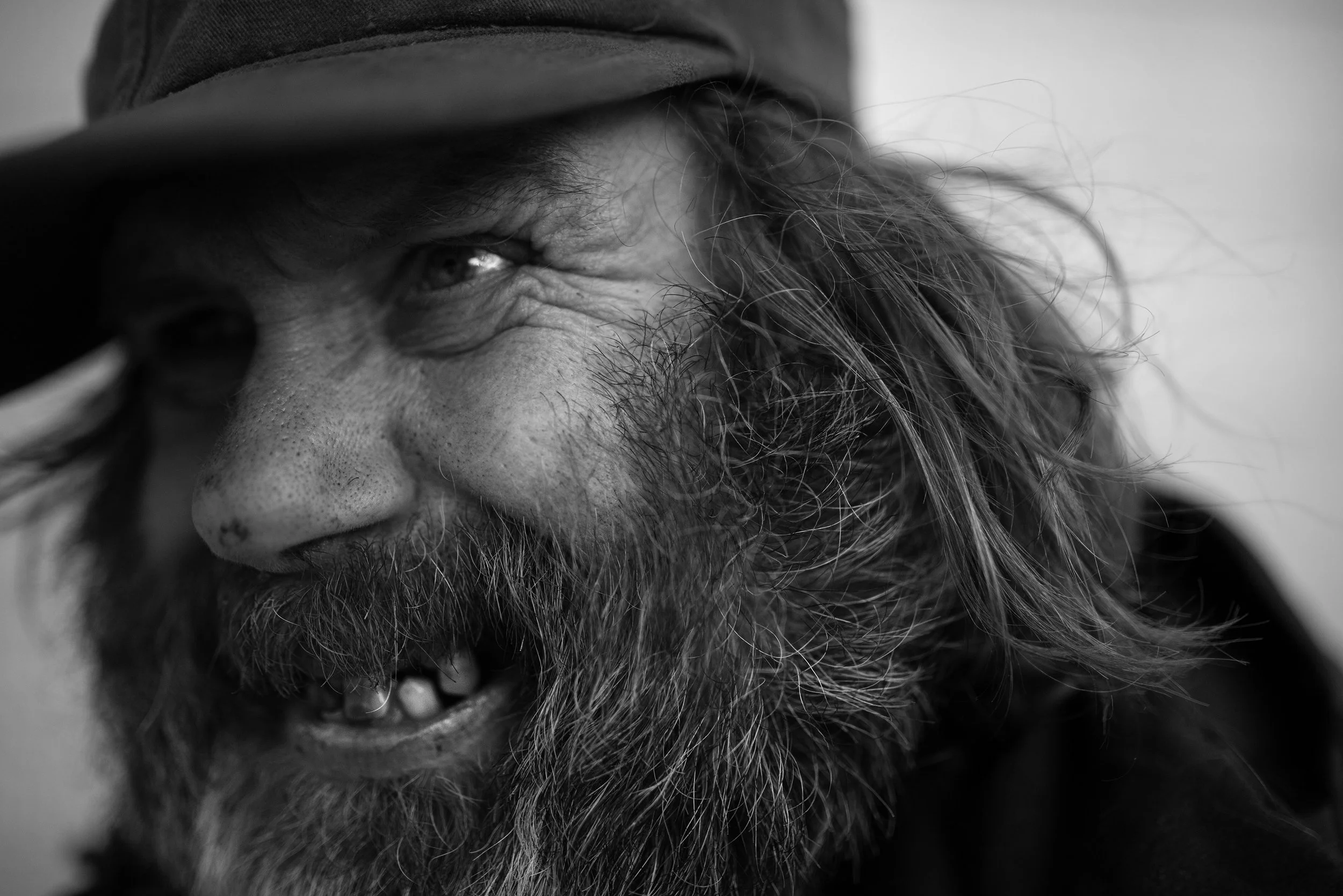 Retrato en negro y blanco de un hombre con barba, cabello largo y un sombrero, sonriendo ligeramente.