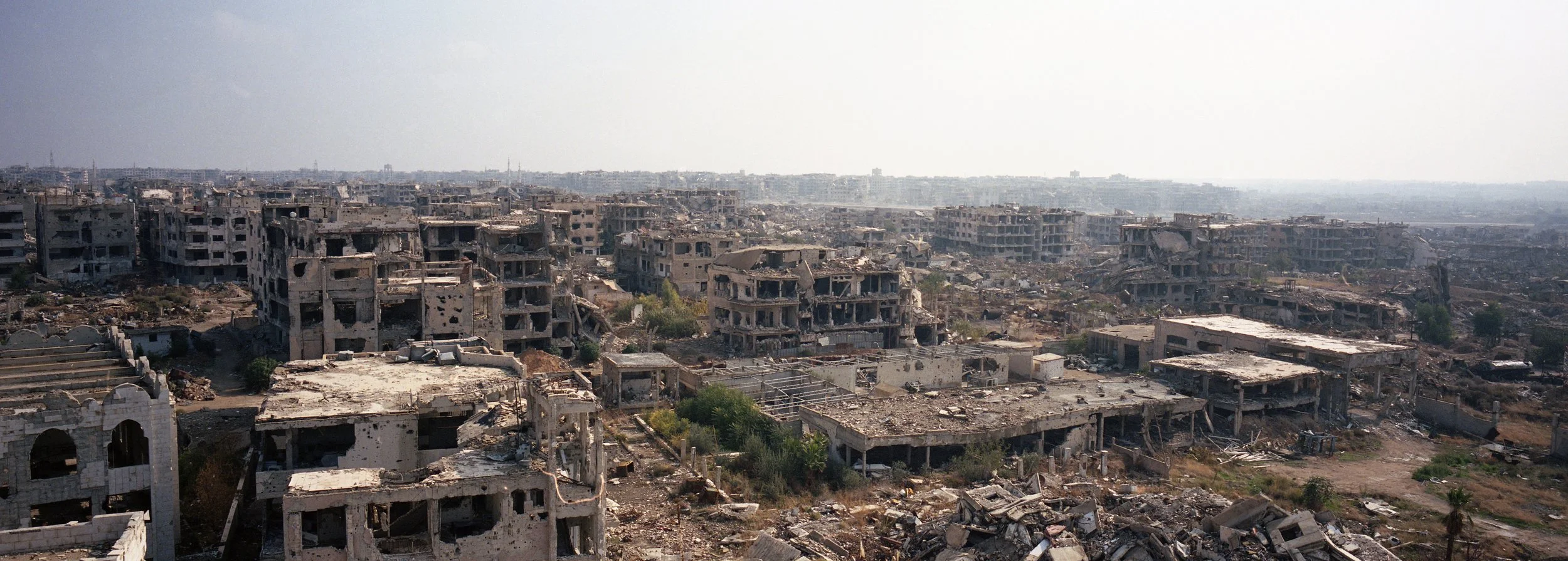 Ciudad destruida con edificios en ruinas y escombros por toda la zona.