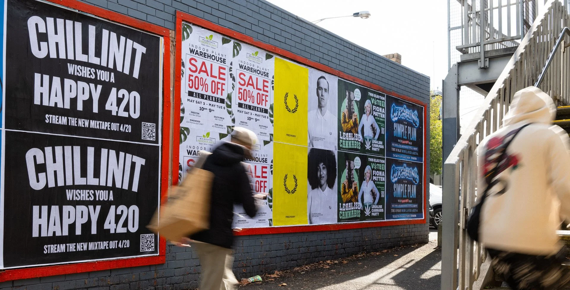 A brick wall with multiple posters and advertisements, including two large signs on the left advertising a music mixtape release, and various smaller flyers about sales, political candidates, and cannabis legalization.
