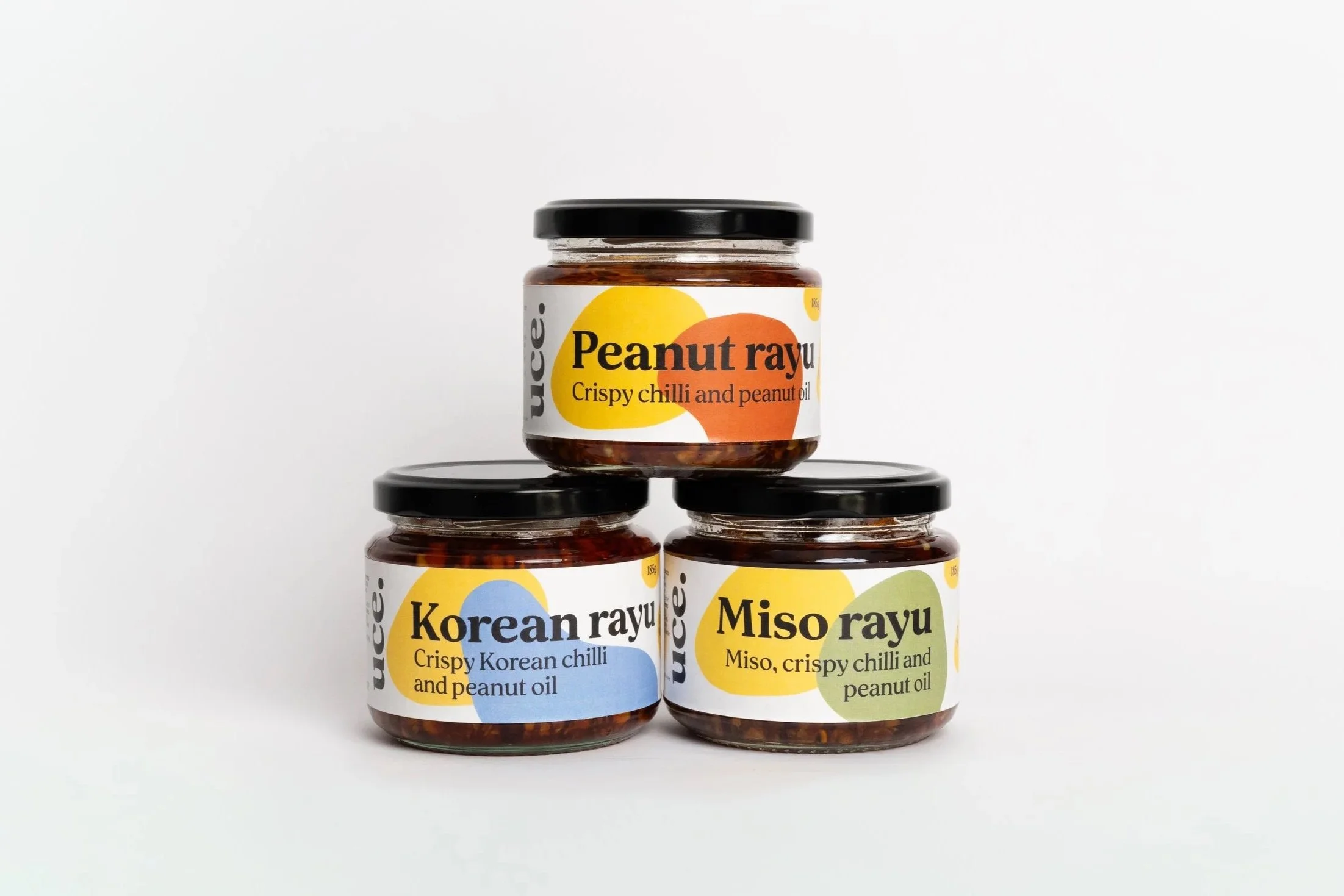 A stack of three uce jars against a white background. On top is peanut rayu. Below on the left Korean rayu and on the right Miso rayu.