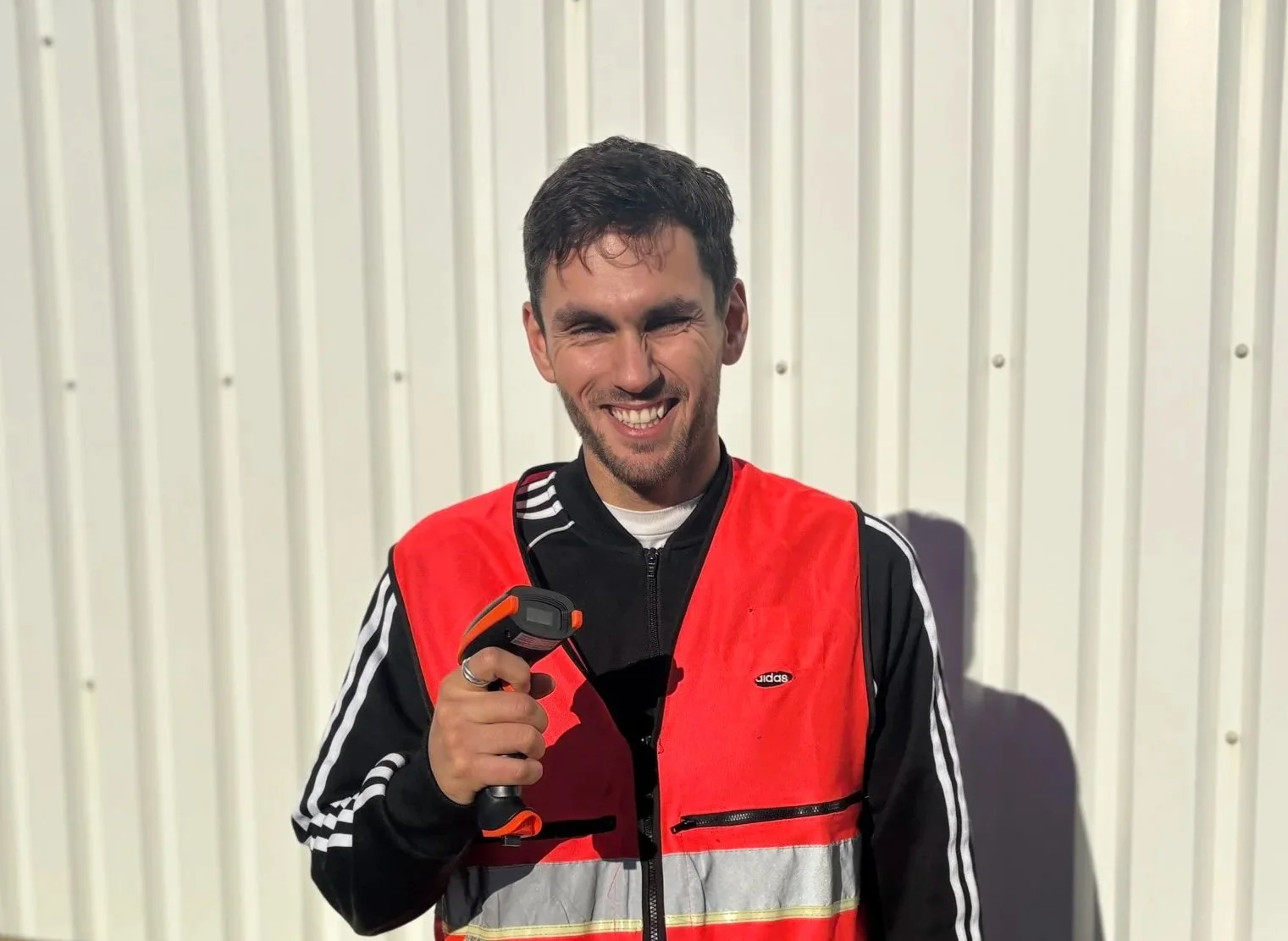 A woman with curly hair wearing glasses, earrings, and a striped shirt, smiling in an indoor setting.