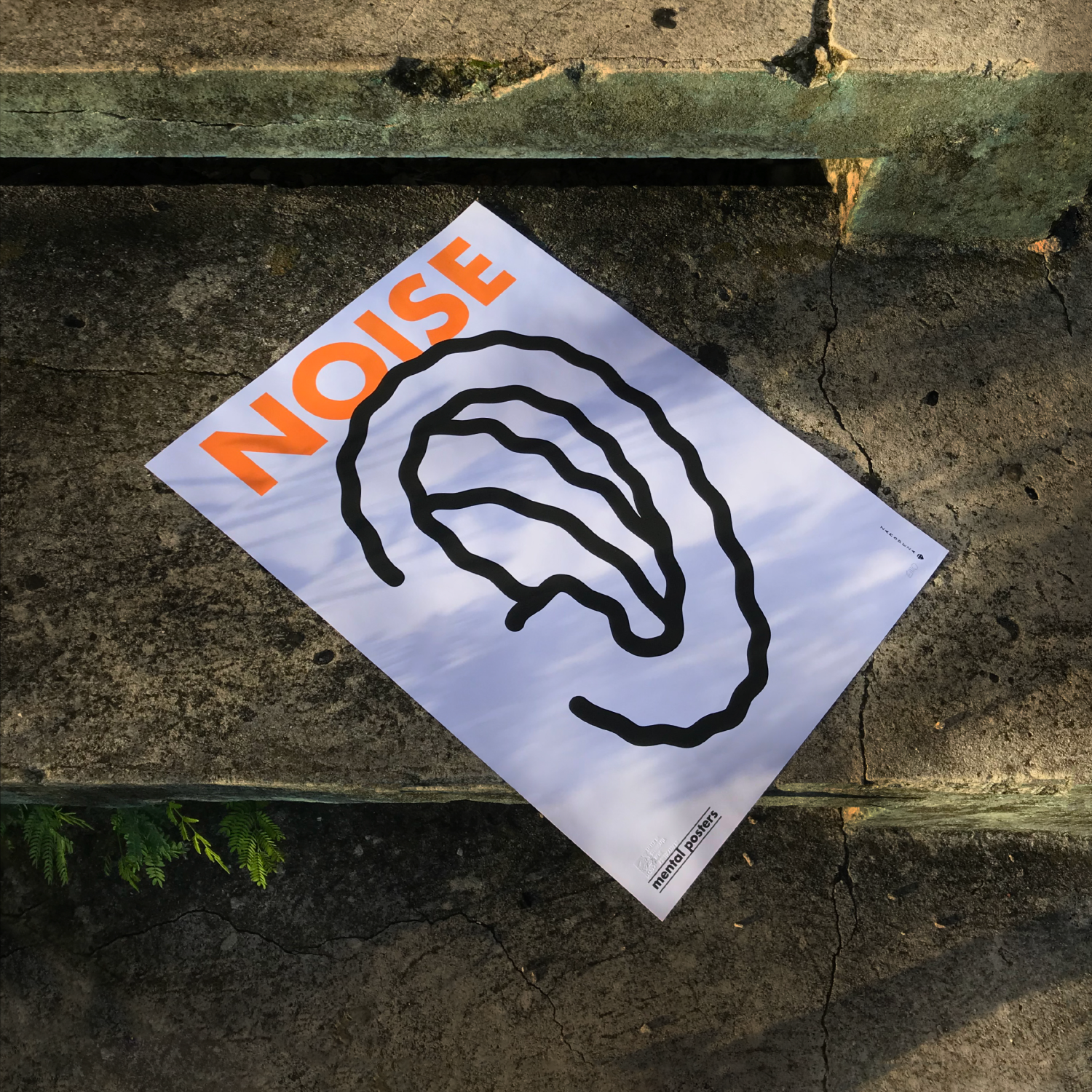 A poster with a black outline of a human ear, placed on a concrete sidewalk. The poster has the word 'NOISE' in large orange letters at the top. The background of the poster appears to reflect the sky with some clouds.