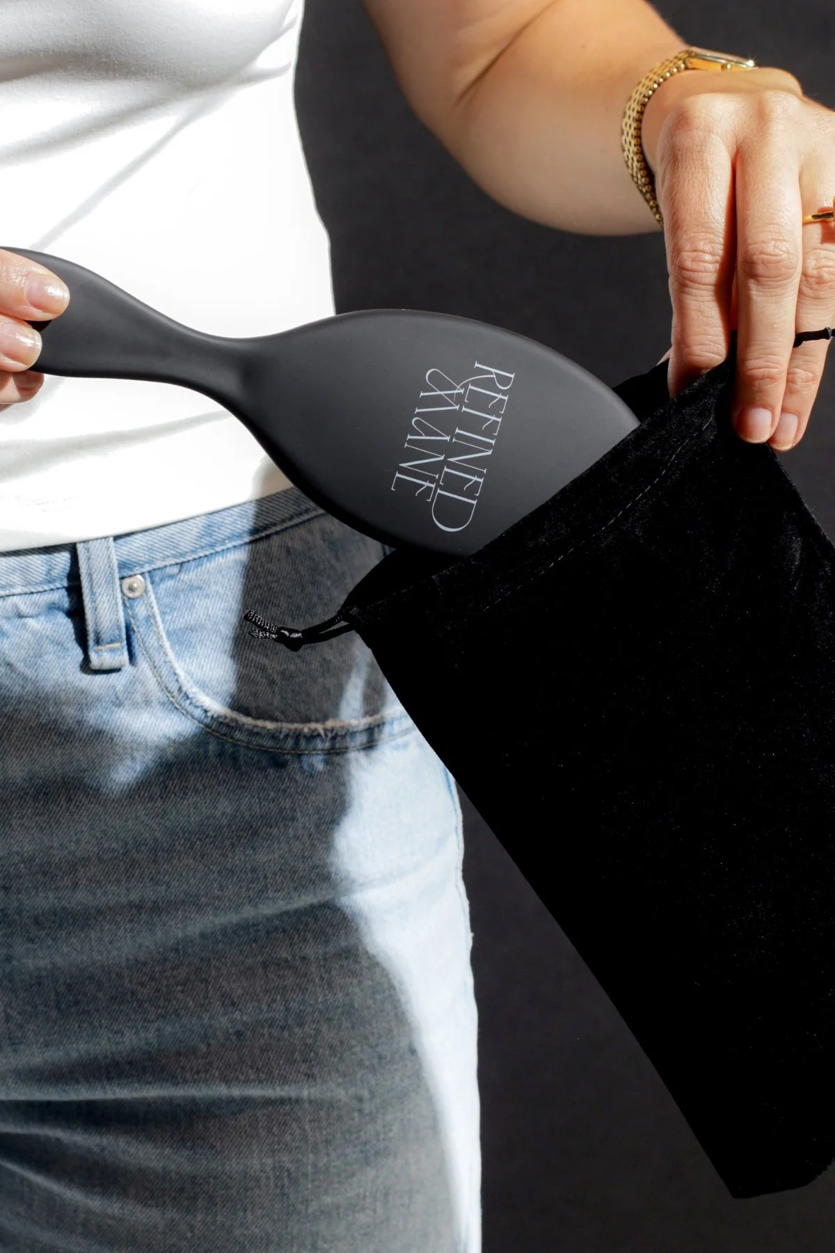 Refined Mane hair brush being placed into a black velvet travel pouch.