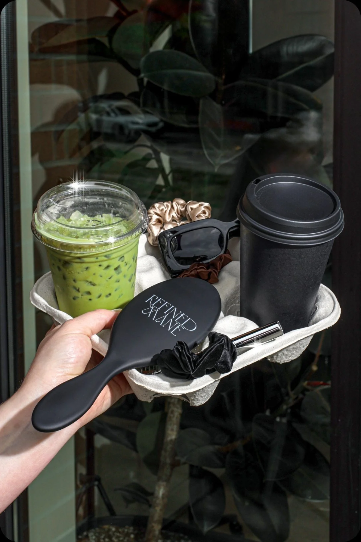 Refined Mane hair brush and silk scrunchies styled with an iced matcha latte and sunglasses in a lifestyle setting.