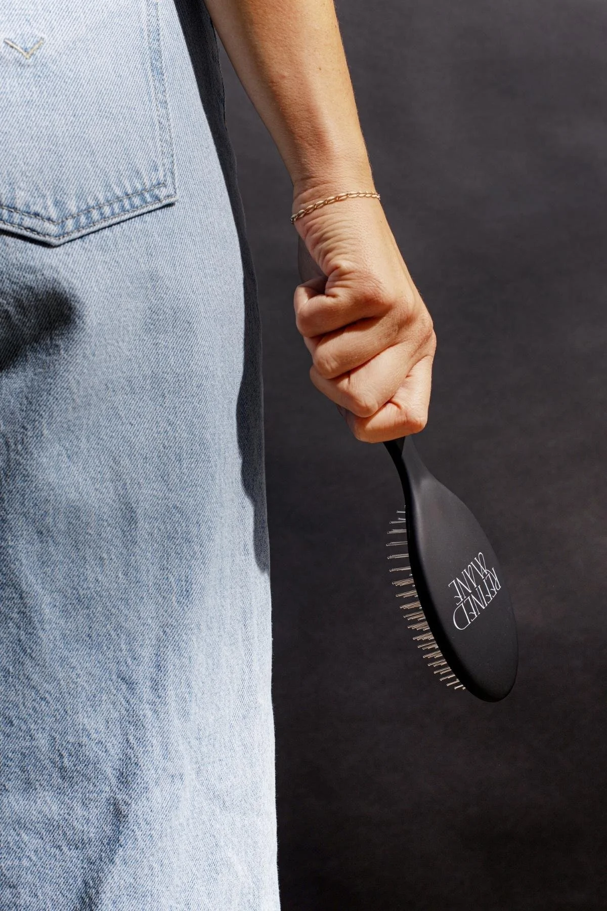Close-up of a hand holding a Refined Mane hair brush.