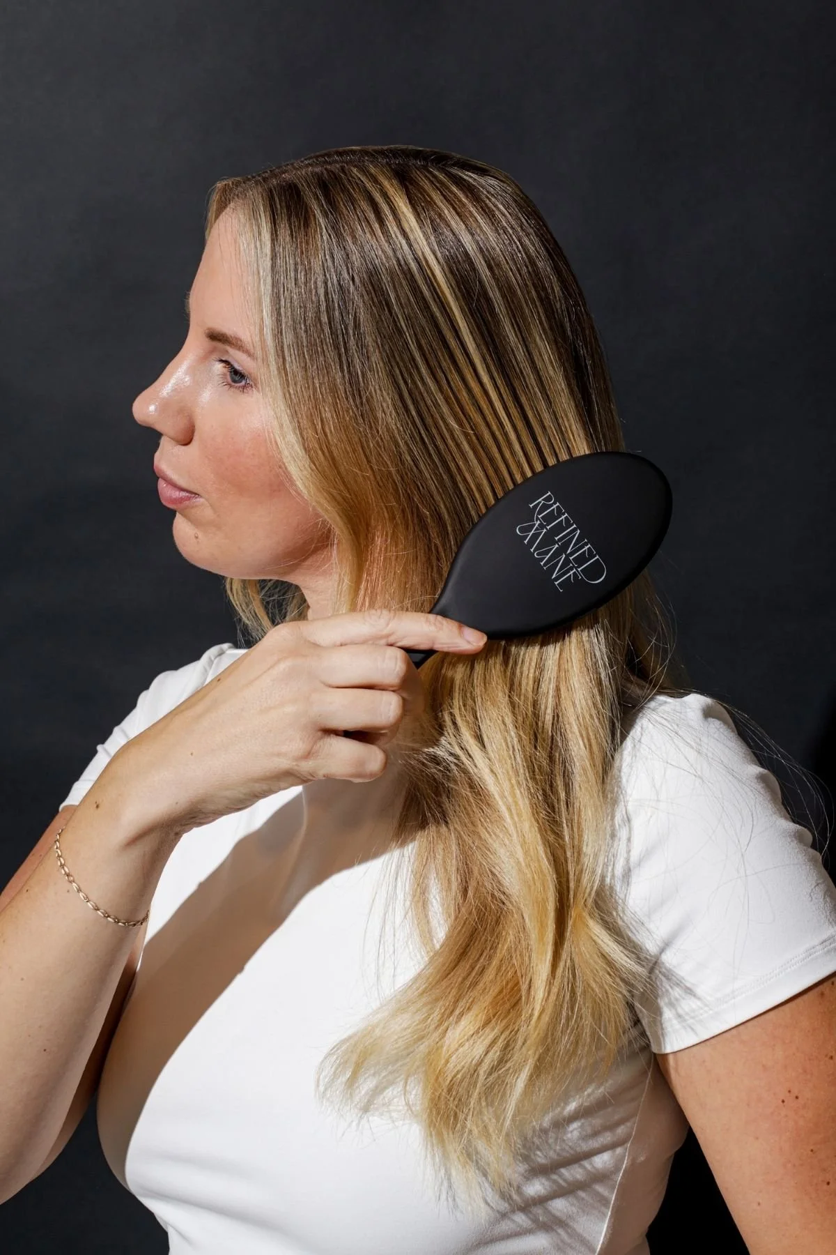 Woman brushing blonde hair with a Refined Mane brush.