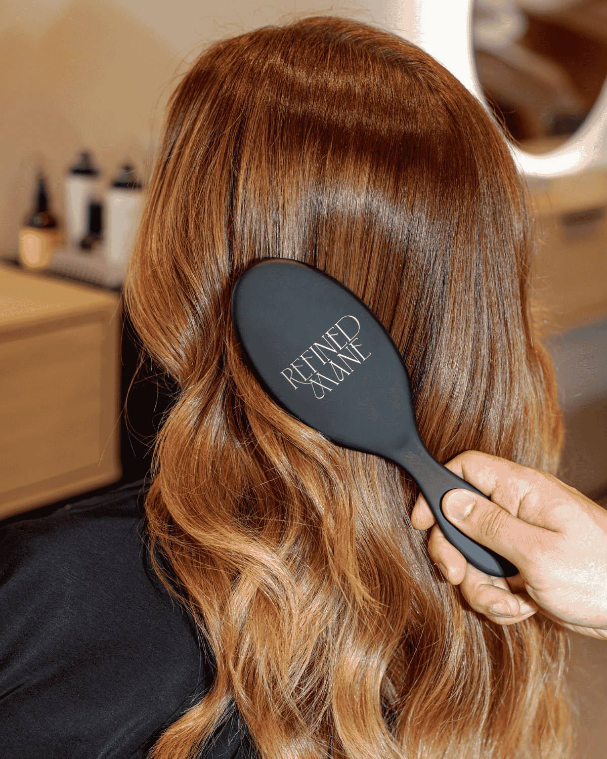 Refined Mane salon-quality brush detangling long, glossy auburn hair from the back.