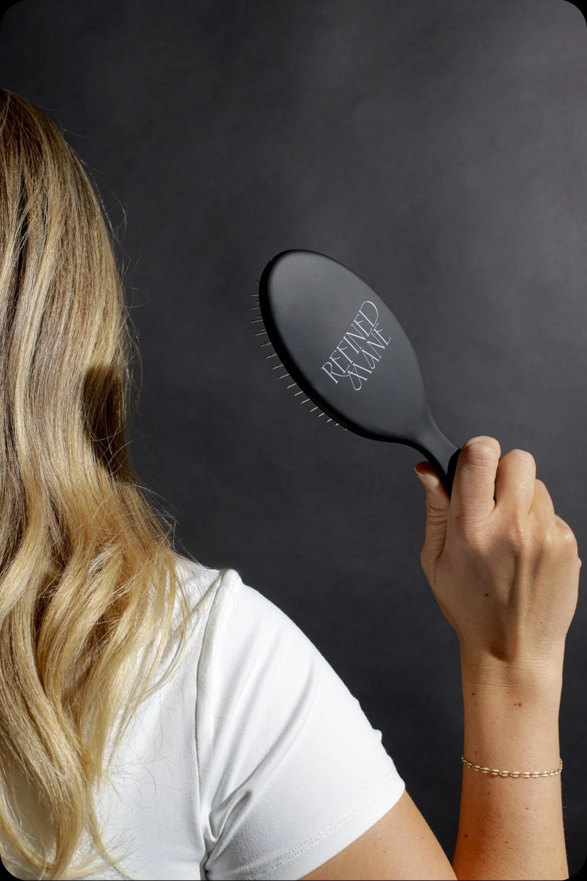 Close-up of a hand holding a Refined Mane hair brush.