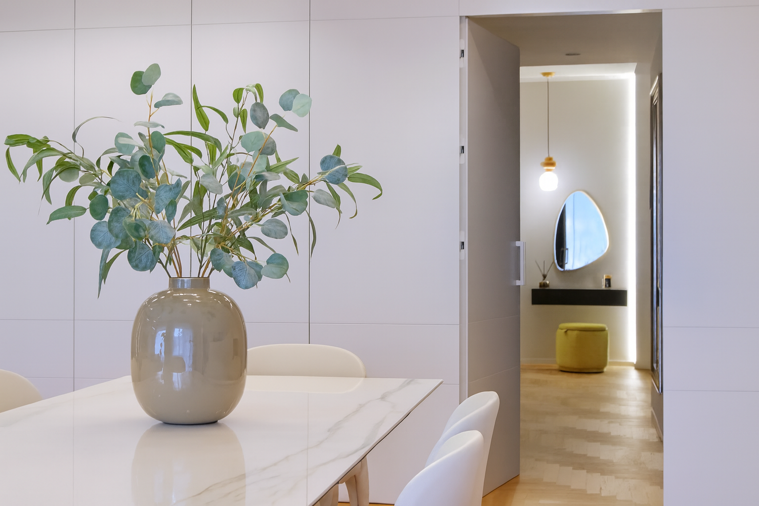 Interior di una stanza moderna con un vaso con foglie verdi su un tavolo bianco.