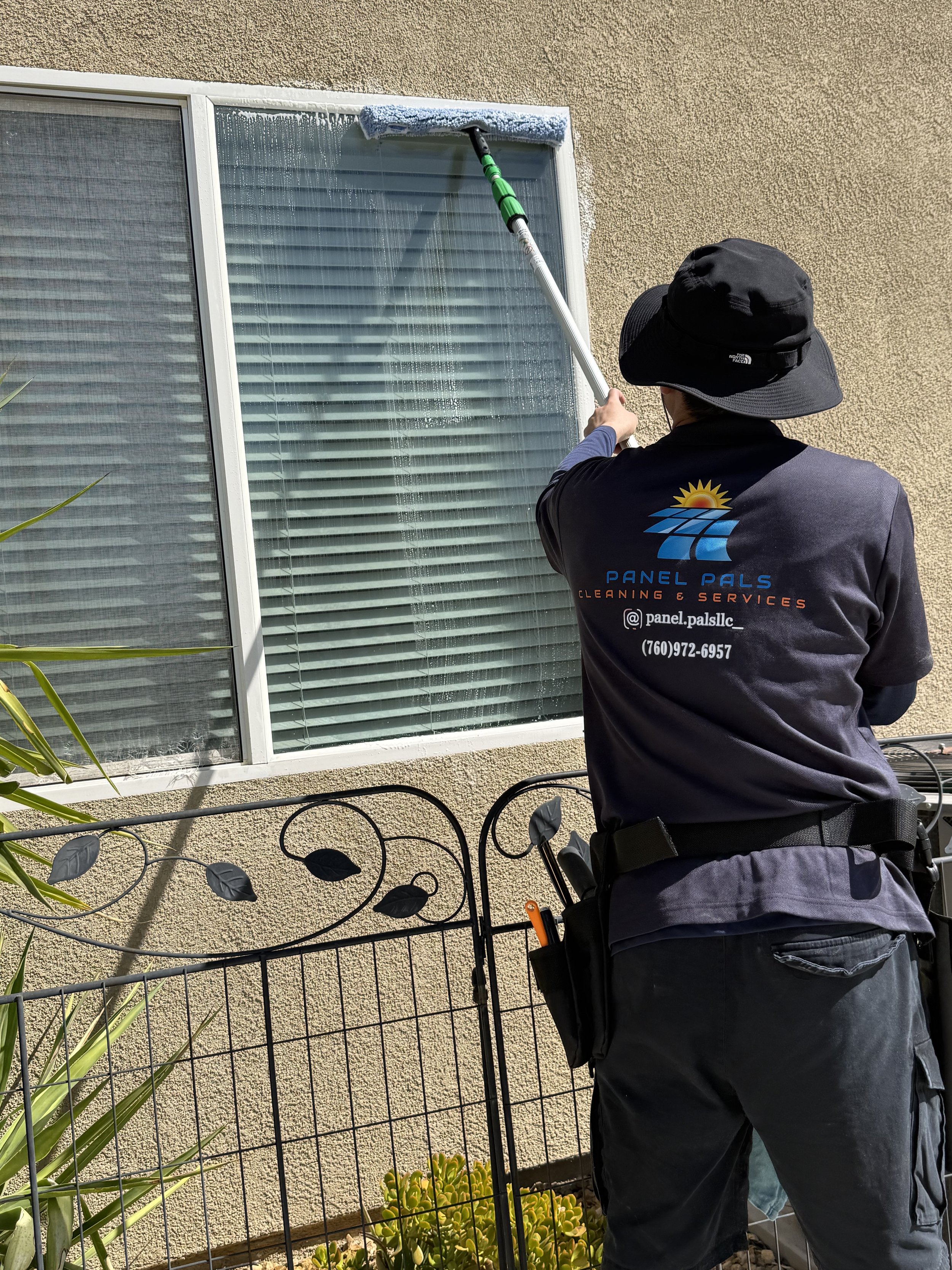 Panel Pals cleaner in branded uniform using an extension pole washer on a residential glass window.
