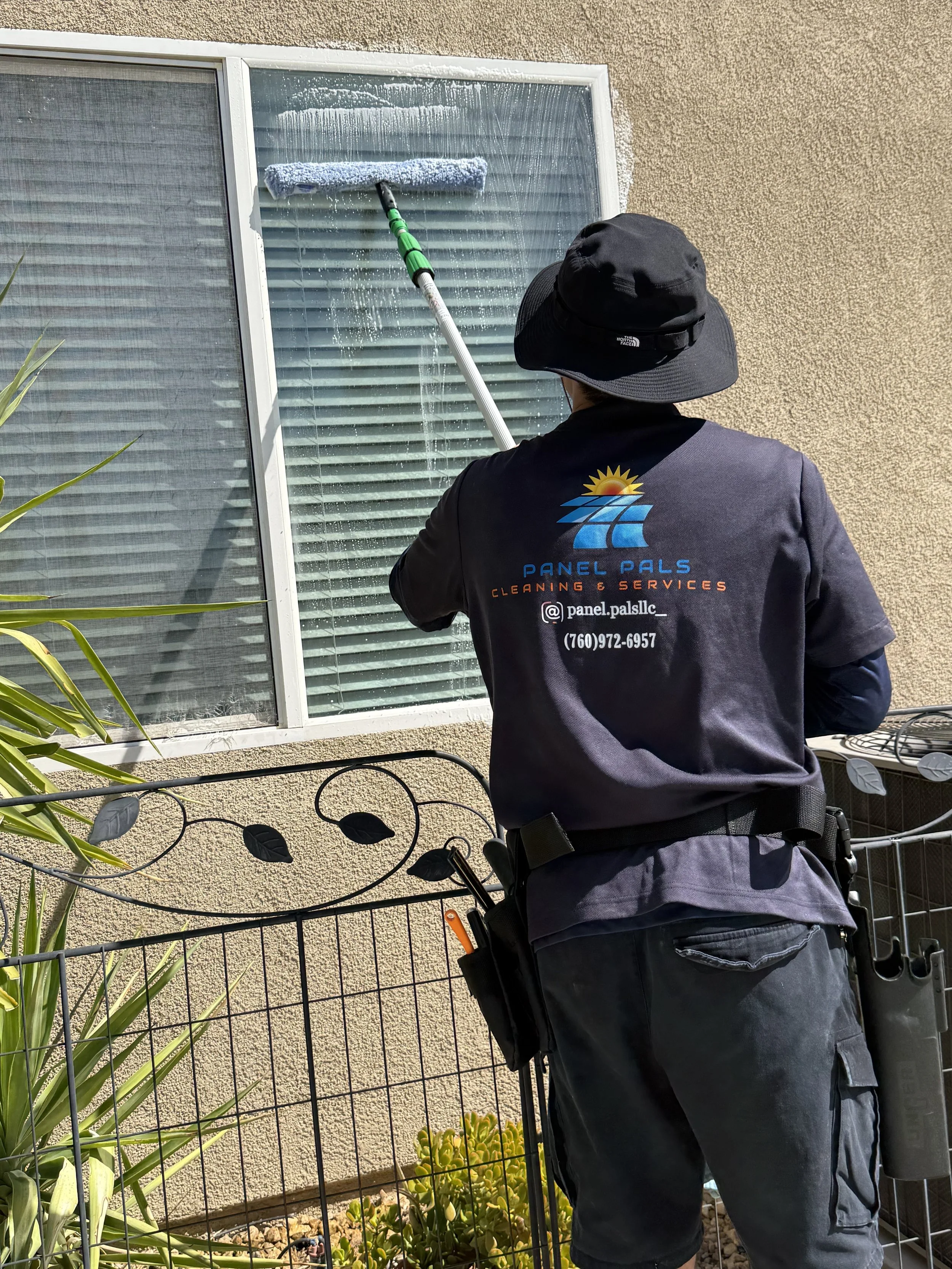 Professional window cleaner from Panel Pals LLC washing exterior home glass with a soft scrubber pole.