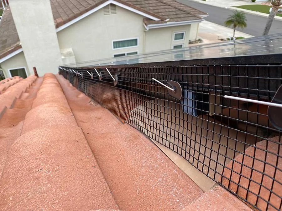 Solar panel bird proofing mesh installed on a clay tile roof using specialized fastening clips.