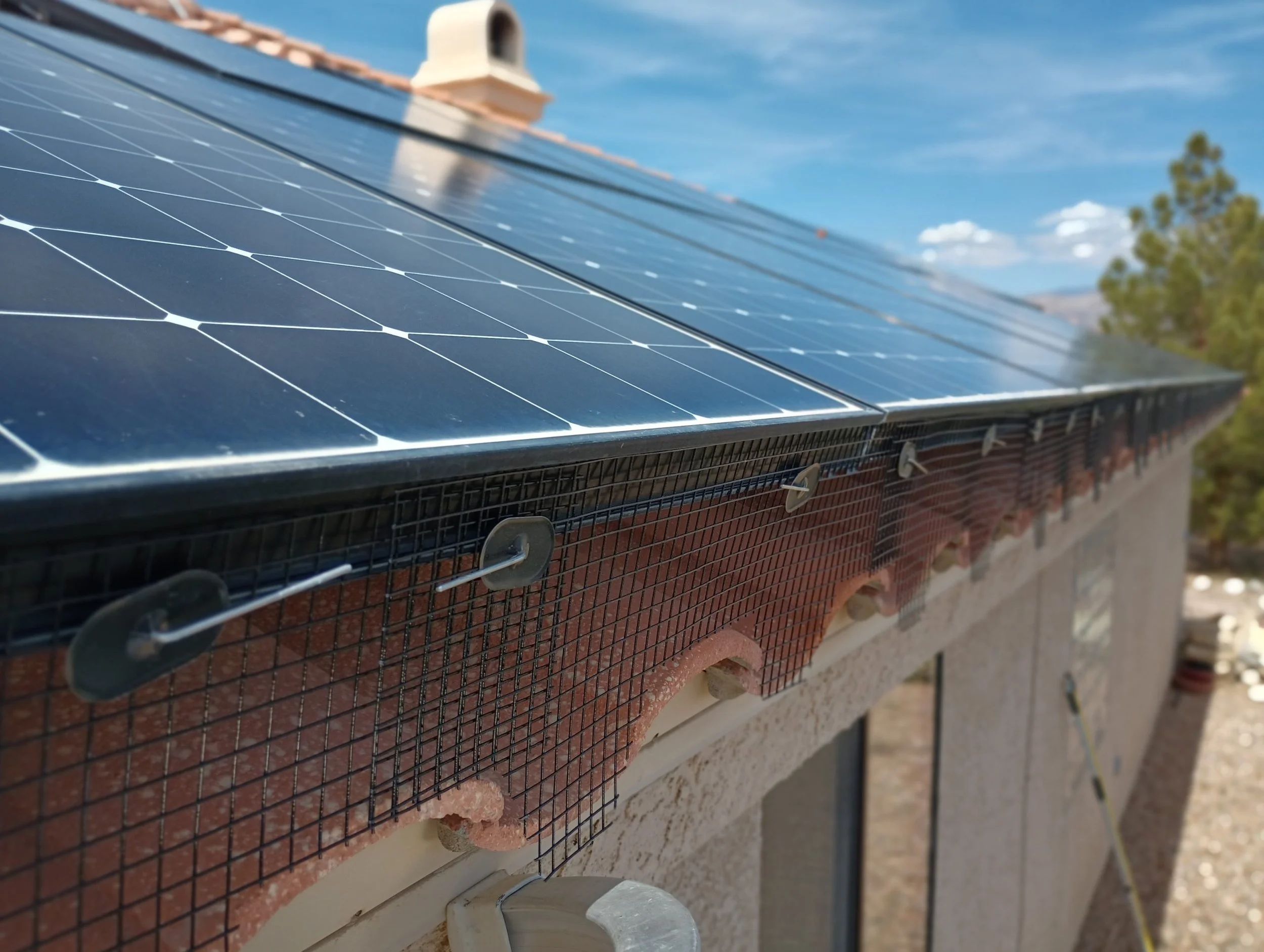 Solar panel bird proofing mesh installed on a clay tile roof using specialized fastening clips.