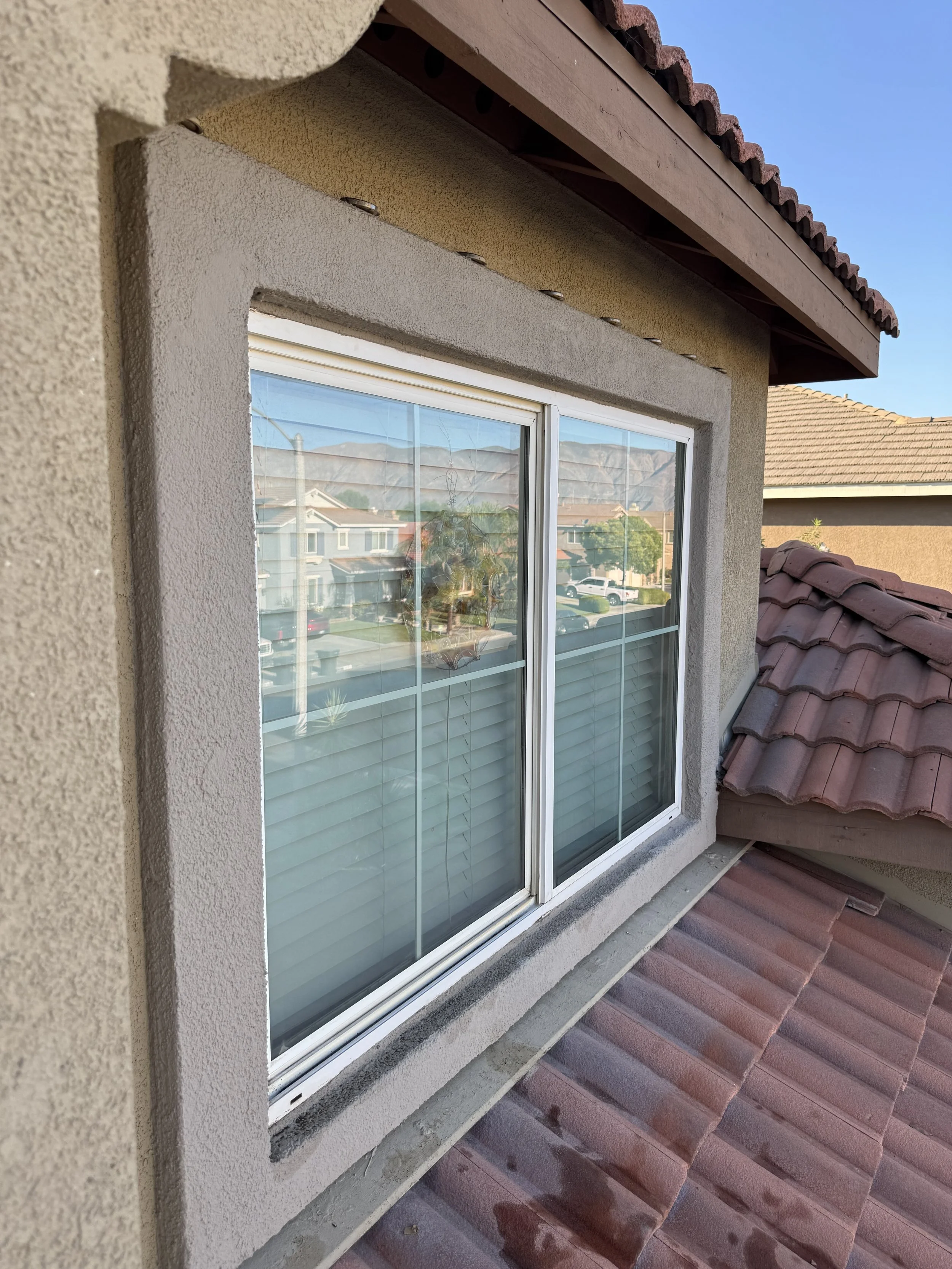 Spotless second-story exterior home window with white trim reflecting the mountains and sky after professional streak-free cleaning.