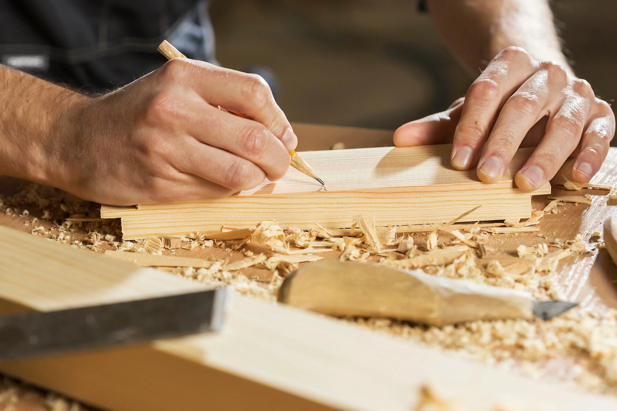 Une personne taille une planche de bois dans un atelier de menuiserie.