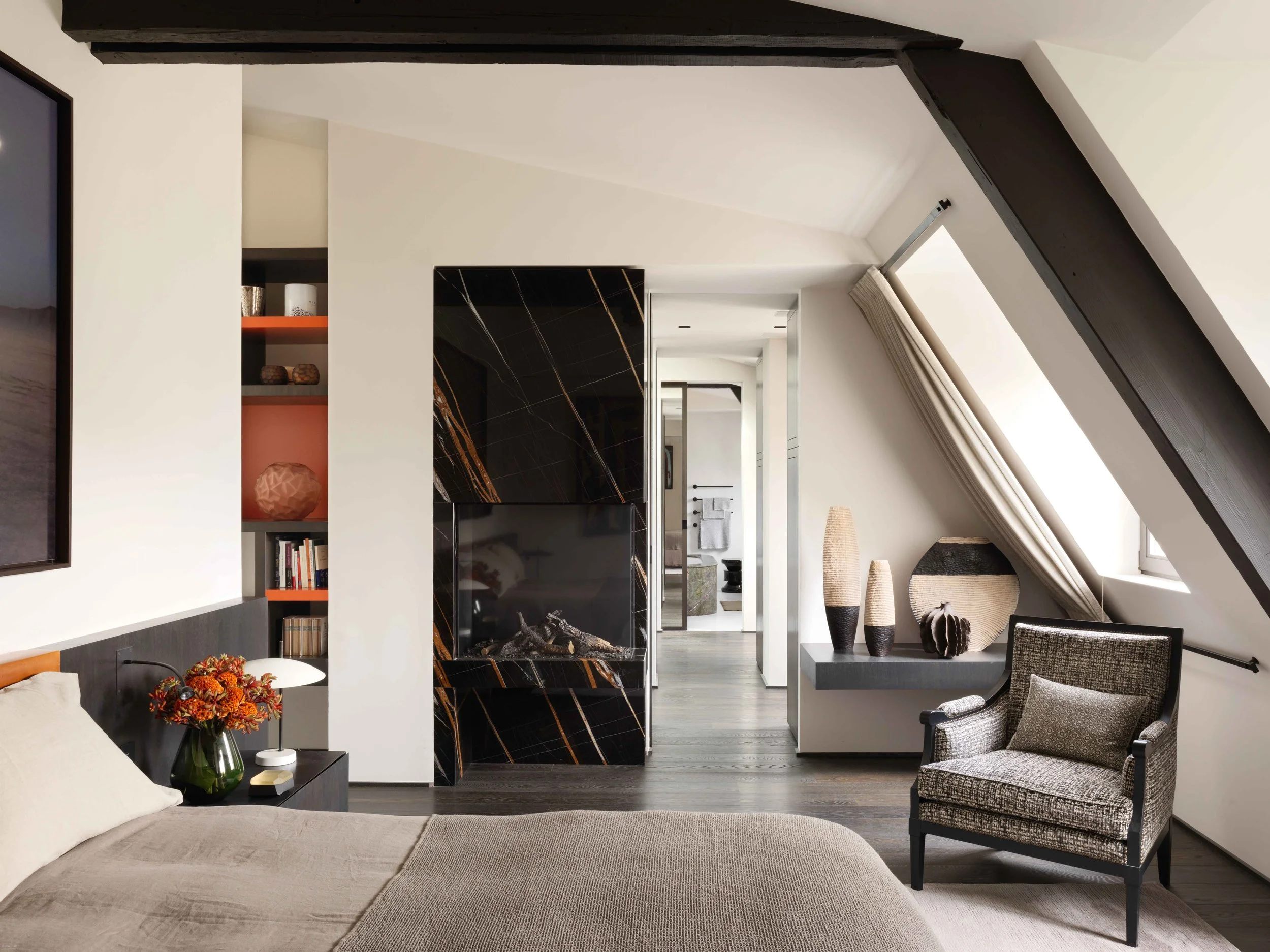 Salon moderne avec cheminée noire en marbre, fauteuil en tissu, étagères avec décorations et livres, décorations en vases sur une console, fer d'angle pour le rideau, fenêtre avec rideau beige