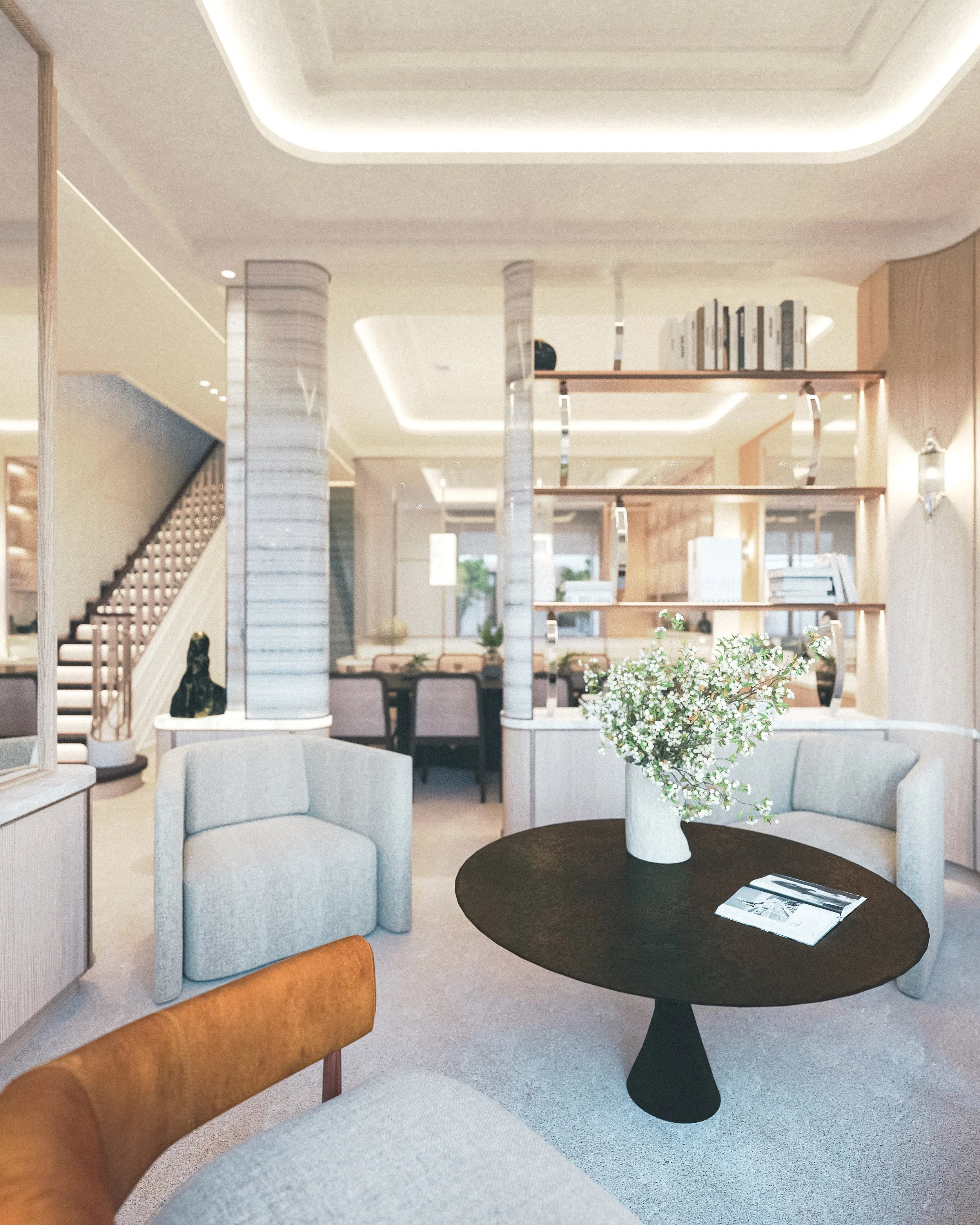 Intérieur d'un salon moderne avec un fauteuil gris, un canapé en cuir marron, une table ronde noire avec un vase de fleurs blanches, étagères en bois derrière, escalier en bois, murs beiges, ambiance chaleureuse et élégante.