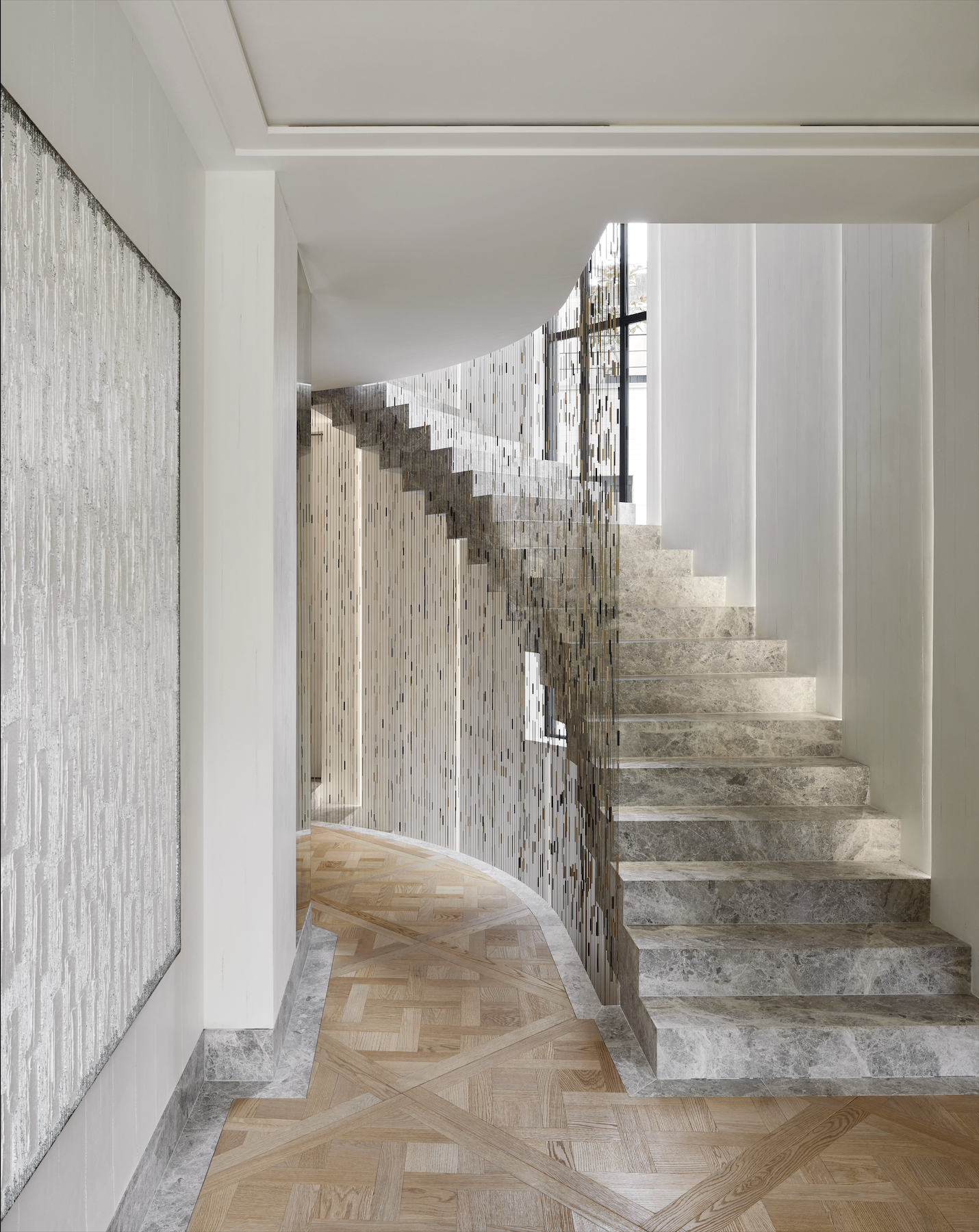 Escalier intérieur avec un mur en mosaïque miroir, sol en parquet et murs blancs.
