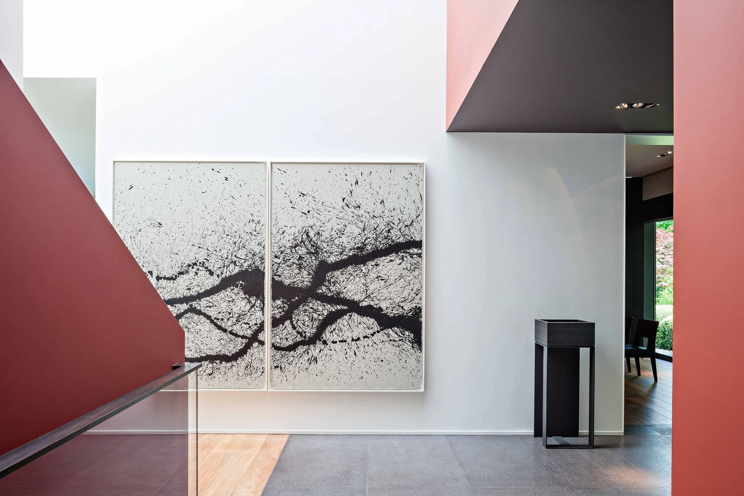 Intérieur moderne avec une grande peinture abstraite en noir et blanc, murs blancs, accents de couleurs rose et gris, et mobilier minimaliste.